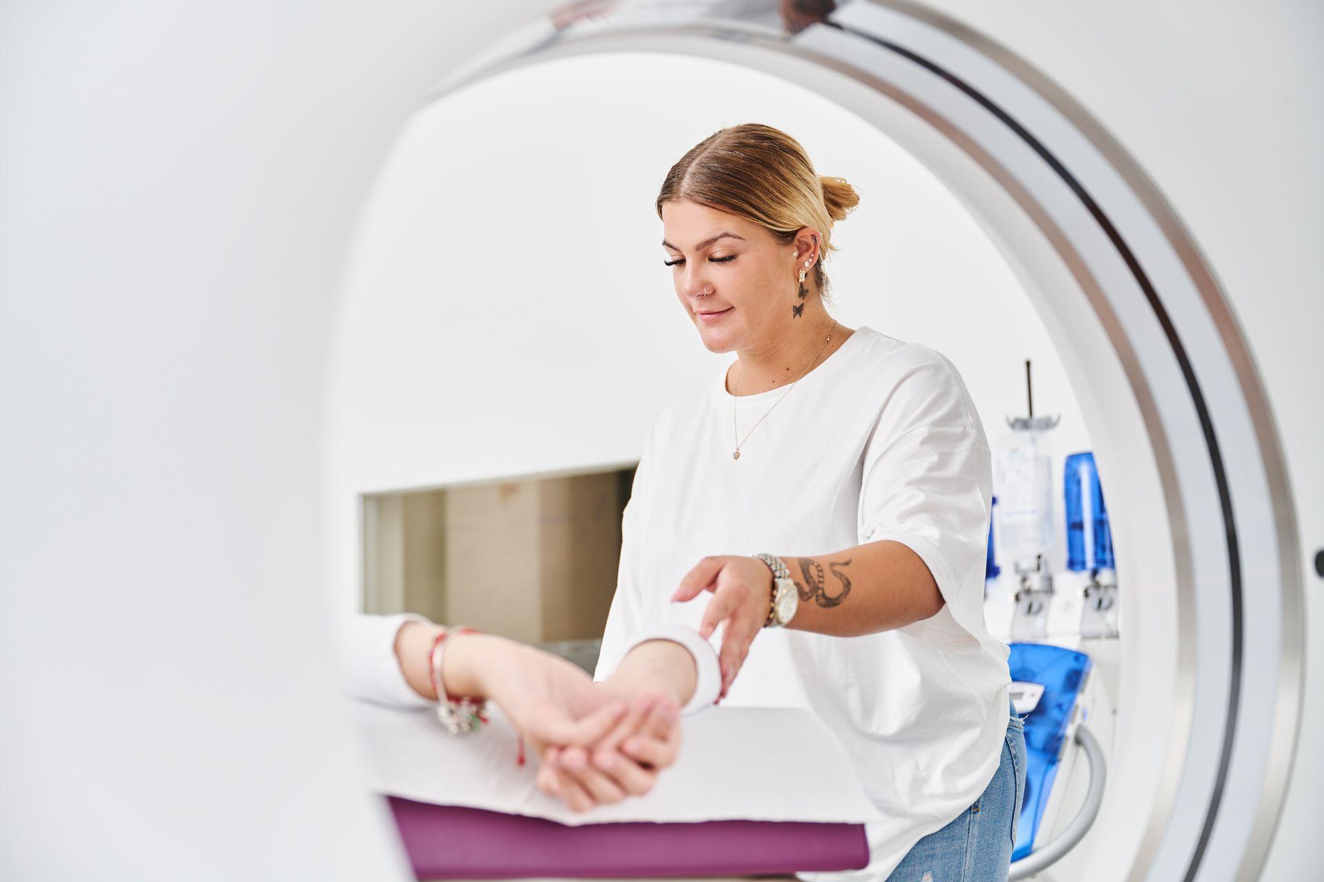 Blick von hinten durch eine CT-Röhre, man sieht eine Patientin, die von einer Medizinischer Fachkraft betreut wird. 