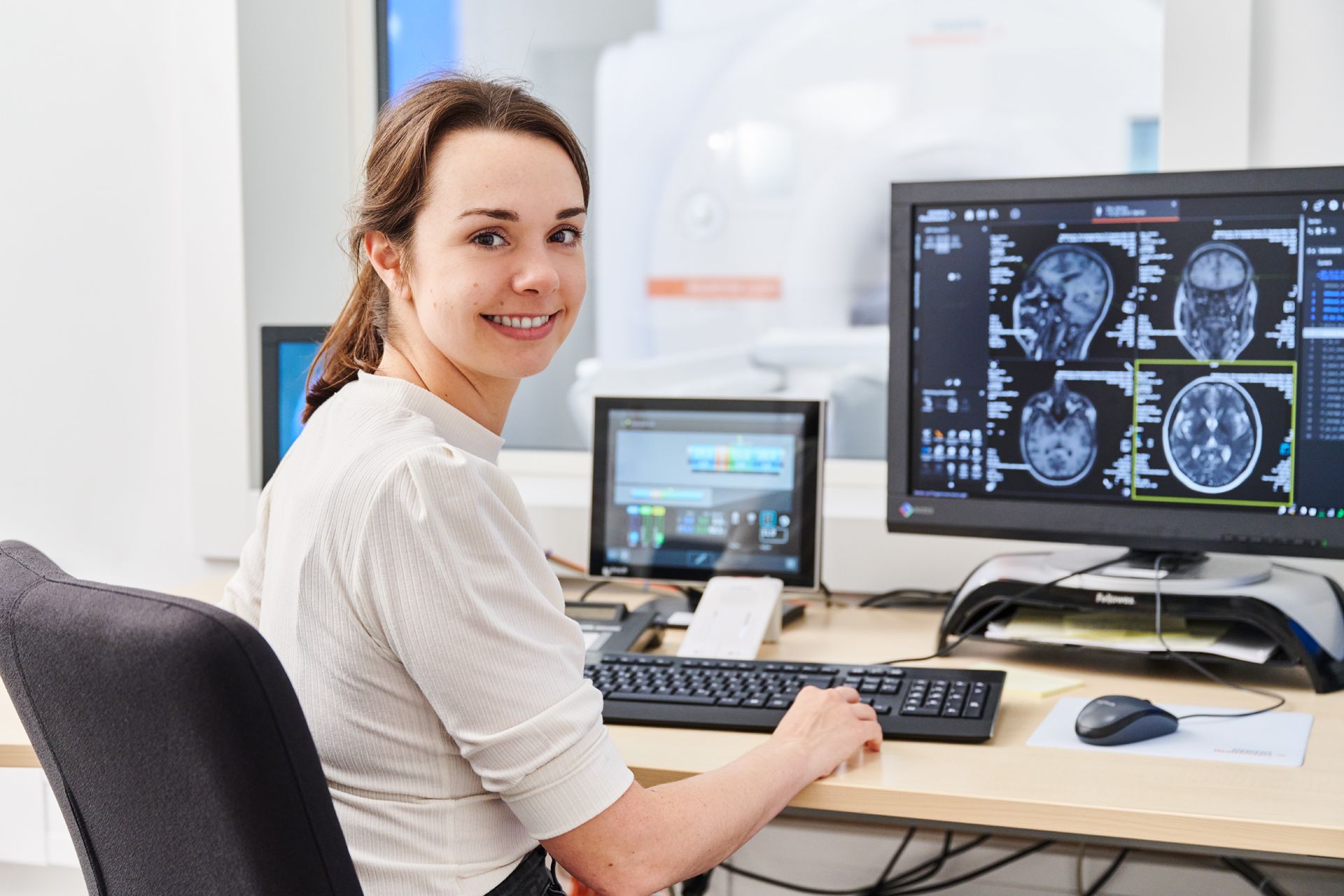 Medizinischer Fachkraft sieht sich die MRT-Bilder eines Kopfes auf einem Computer Bildschirm an.